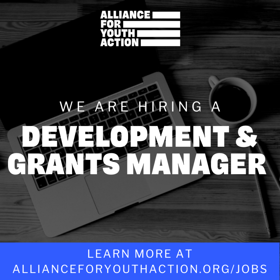 A graphic that reads "We are hiring a Development & Grants Manager" in white text on top of a black and white image of a laptop. At the top of the graphic is a white logo of the Alliance for Youth Action. At the bottom, is a blue banner with white text that says" Learn more at allianfeforyouthaction.org"
