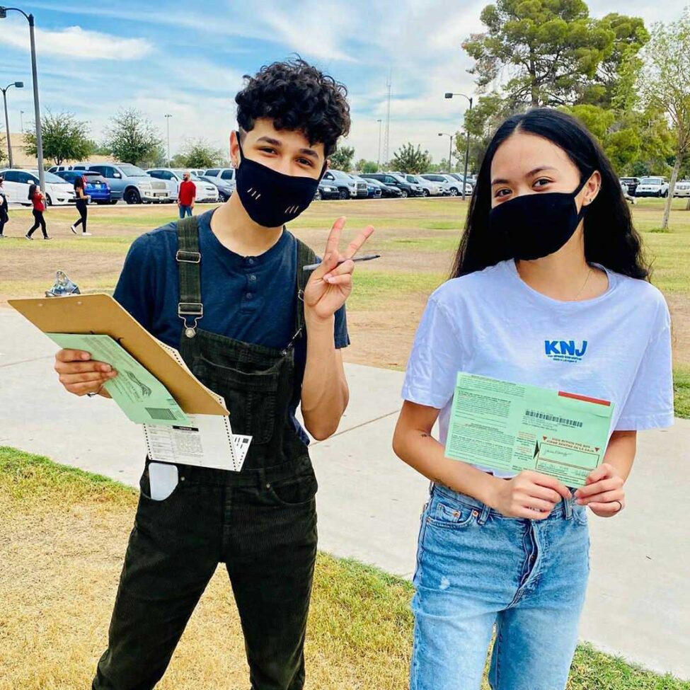 Two young organizers with masks on and clipboards