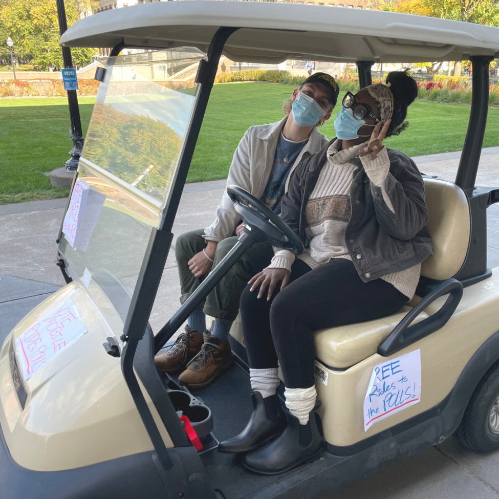 photo of people driving students to polls in a golf cart